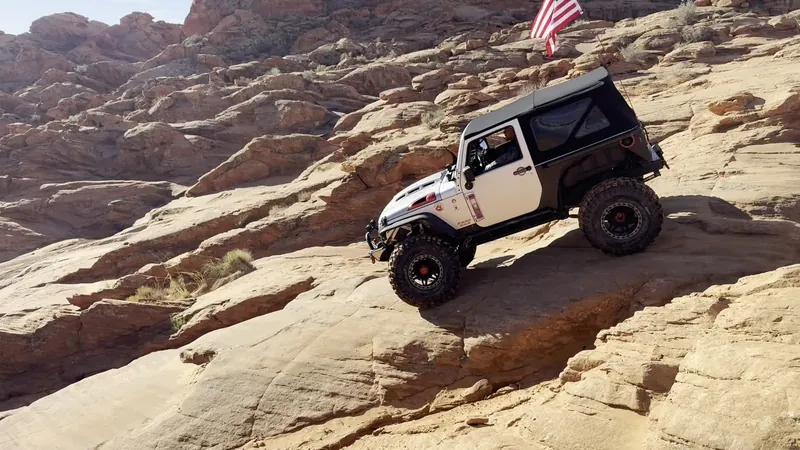 White Jeep crossing uneven rock