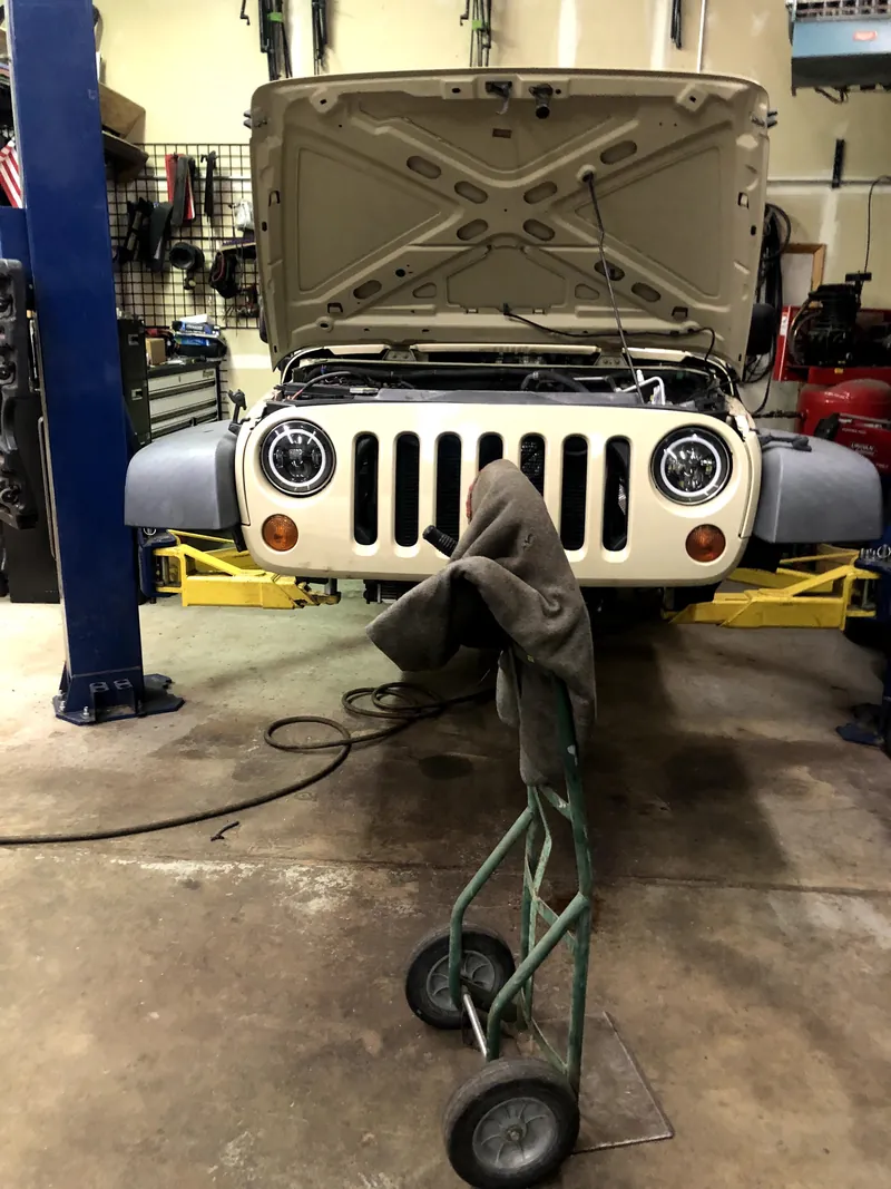White Jeep with its hood open on a workshop lift